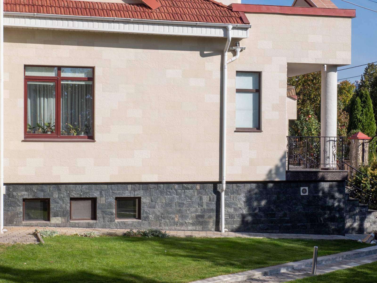 Fațadă laterală cu ferestre, balcon cu balustradă forjată și piatră flexibilă bej